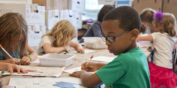 Crianças em mesa de escola escrevendo